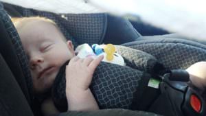 infant with pacifier sleeping in car seat