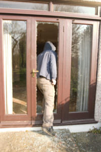 burglar stepping through shattered glass door