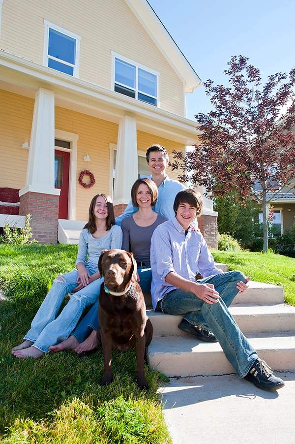 family with dog sitting on steps outside a house