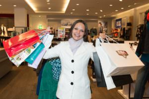 woman holding up several shopping bags inside a store