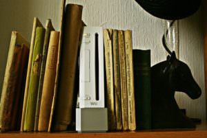 picture of a Wii game console tucked between books on a full bookshelf