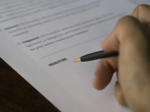 picture of someone holding a pen about to sign a contract
