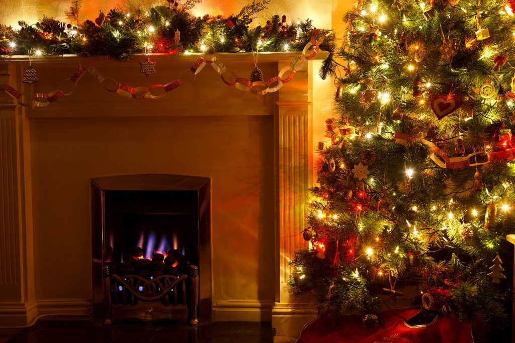 picture of a decorated Christmas tree next to a fireplace with garland on the mantel