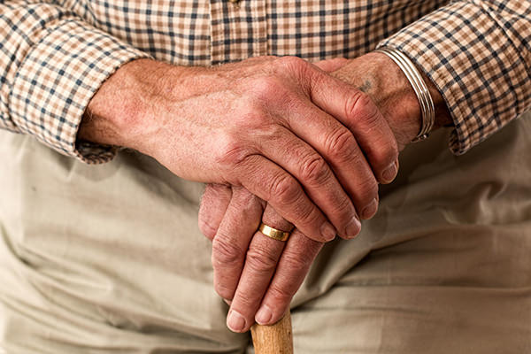 picture of an older man's hands crossed over a cane or walking stick