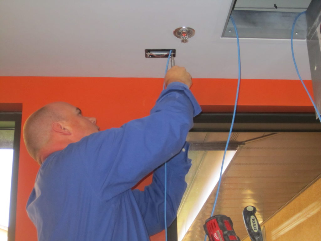 Picture of technician Josh pulling wiring down from ceiling