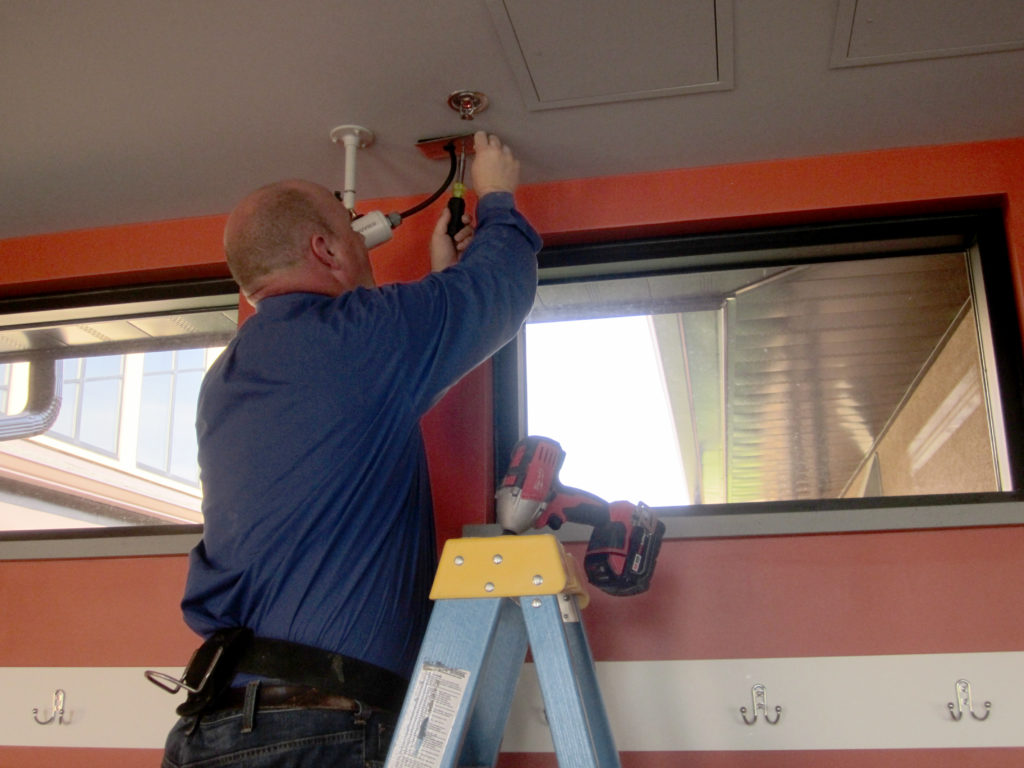 Picture of technician Josh attaching a silver panel to the ceiling to protect the camera wiring