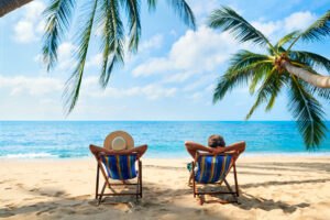 Two people sitting in chairs on a beach looking at the ocean.