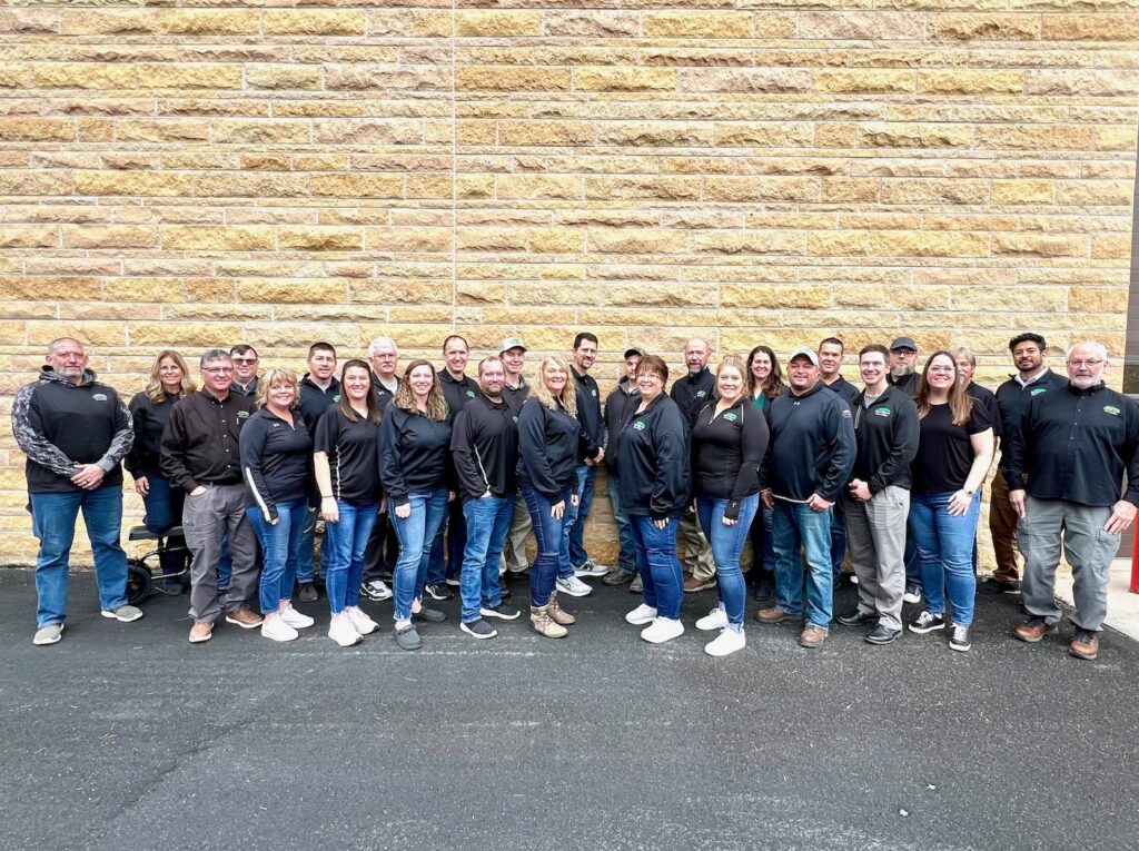 All Heartland Employees posing and smiling side by side with matching jackets